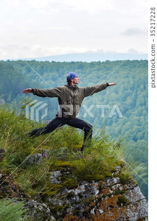 Man traveller practicing yoga warrior pose on the Man traveller practicing yoga warrior pose on the 35217228