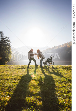 Senior couple with wheelchair in autumn nature. 35225342