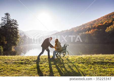 Senior couple with wheelchair in autumn nature. 35225347