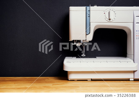 Sewing machine on wooden table and black wall 35226388