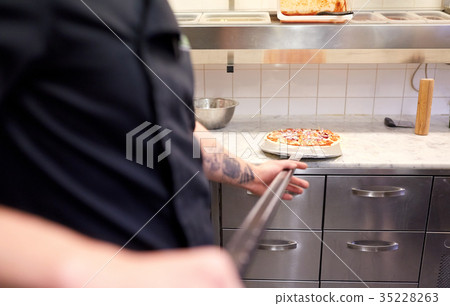 cook or baker with pizza on peel at pizzeria cook or baker with pizza on peel at pizzeria 35228263