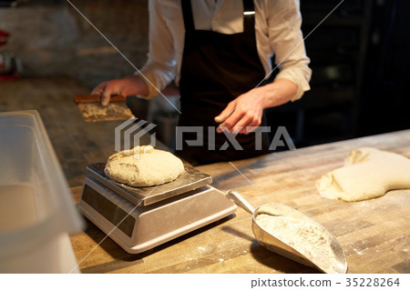 chef or baker weighing dough on scale at bakery chef or baker weighing dough on scale at bakery 35228264