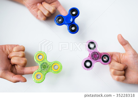 close up of hands playing with fidget spinners 35228318
