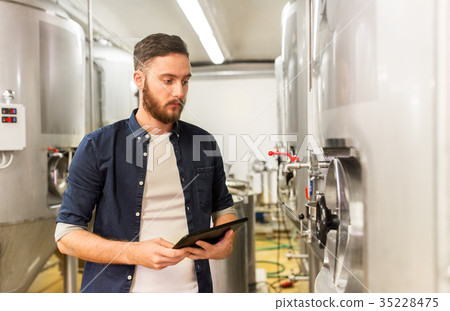 man with tablet pc at craft brewery or beer plant 35228475