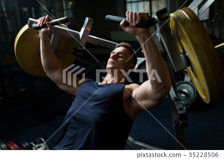 man doing chest press on exercise machine in gym 35228506