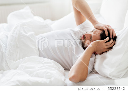 man in bed at home suffering from headache man in bed at home suffering from headache 35228542