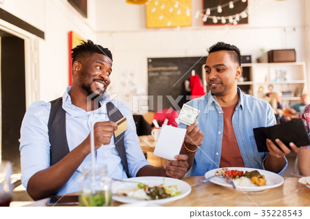happy friends with money paying bill at restaurant 35228543