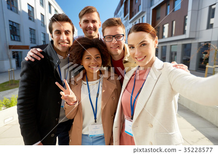 team with conference badges taking selfie in city 35228577