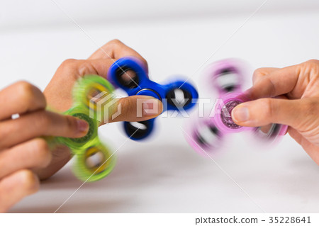 close up of hands playing with fidget spinners 35228641