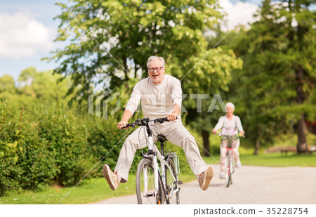 happy senior couple riding bicycles at summer park 35228754