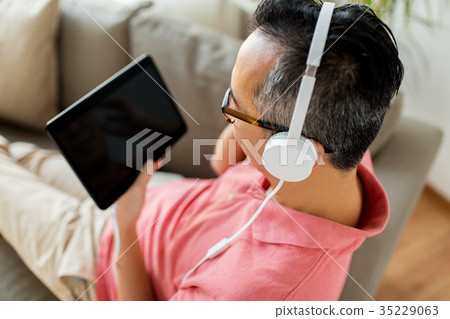 man with tablet pc and headphones at home man with tablet pc and headphones at home 35229063