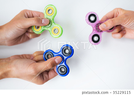 close up of hands playing with fidget spinners 35229115