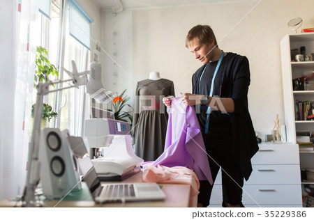 fashion designer with cloth making dress at studio 35229386
