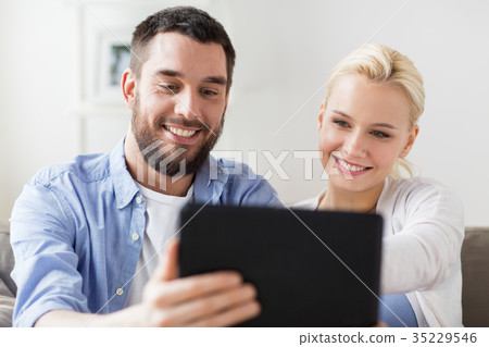 smiling happy couple with tablet pc at home 35229546