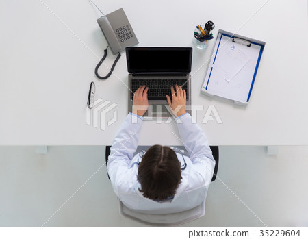 woman doctor typing on laptop at clinic woman doctor typing on laptop at clinic 35229604