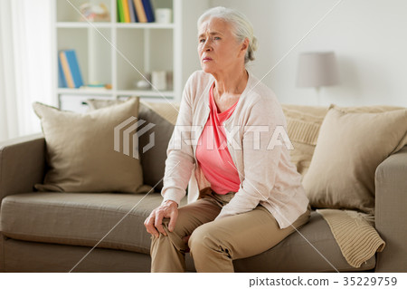 senior woman suffering from pain in leg at home senior woman suffering from pain in leg at home 35229759