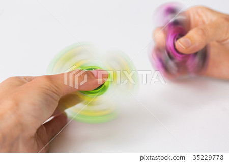 close up of hands playing with fidget spinners 35229778
