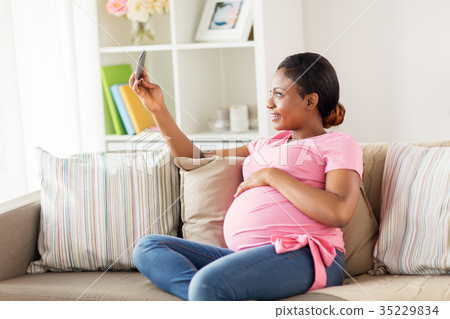 pregnant woman taking smartphone selfie at home 35229834