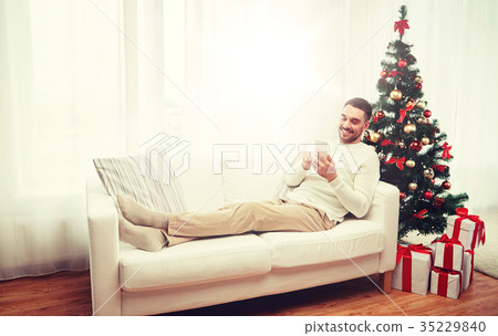 smiling man with smartphone at home for christmas smiling man with smartphone at home for christmas 35229840