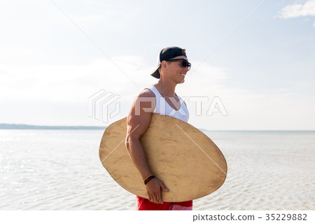 happy young man with skimboard on summer beach 35229882
