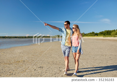 happy couple walking along summer beach happy couple walking along summer beach 35230283