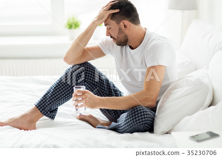 man in bed with glass of water at home 35230706