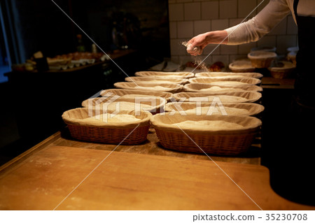 baker with baskets for dough rising at bakery baker with baskets for dough rising at bakery 35230708