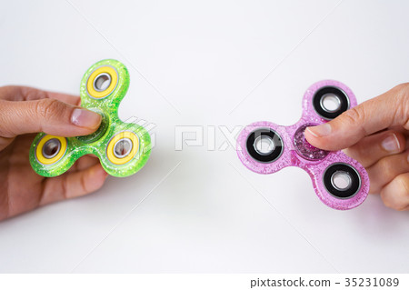 close up of two hands playing with fidget spinners 35231089