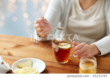 close up of ill woman drinking tea with lemon close up of ill woman drinking tea with lemon 35231787