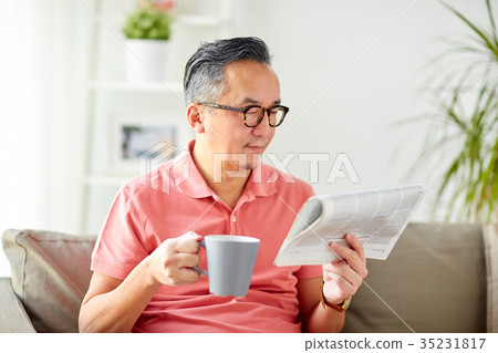 man drinking coffee and reading newspaper at home man drinking coffee and reading newspaper at home 35231817