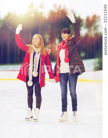 women or friends waving hands on skating rink 35231849