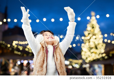 happy girl wearing earmuffs over christmas lights happy girl wearing earmuffs over christmas lights 35231916