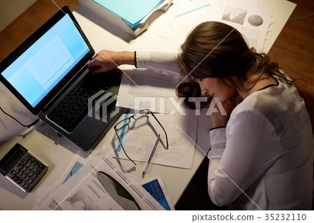 tired woman sleeping on office table at night 35232110