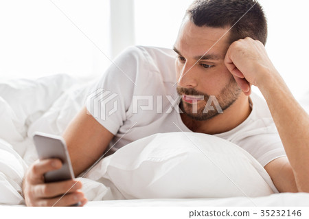 close up of man with smartphone in bed in morning close up of man with smartphone in bed in morning 35232146
