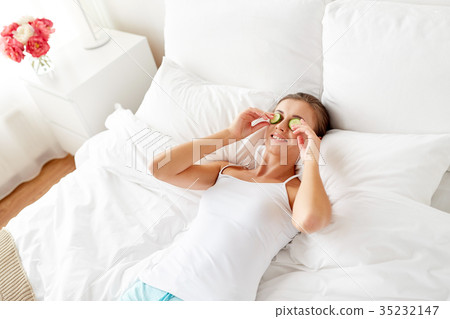 beautiful woman applying cucumbers to face at home 35232147