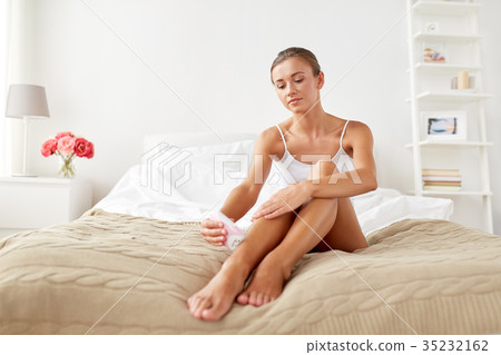 woman with epilator removing hair on legs at home 35232162