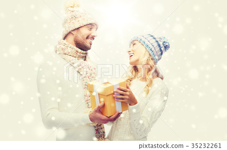smiling couple in winter clothes with gift box smiling couple in winter clothes with gift box 35232261