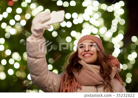 young woman taking selfie over christmas tree 35232822