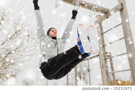 young man exercising on horizontal bar in winter young man exercising on horizontal bar in winter 35232973