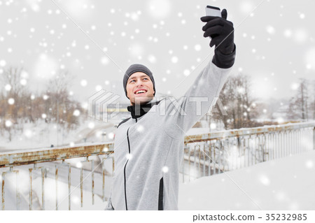 man taking selfie with smartphone in winter man taking selfie with smartphone in winter 35232985