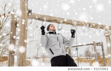 young man exercising on horizontal bar in winter 35233001