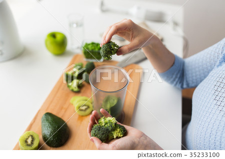 woman hand adding broccoli to measuring cup woman hand adding broccoli to measuring cup 35233100