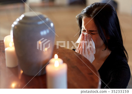 woman with cremation urn at funeral in church 35233159