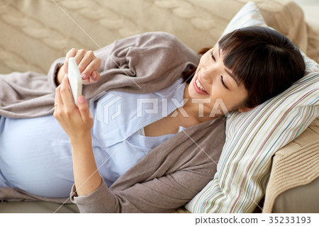 happy pregnant woman with smartphone at home 35233193