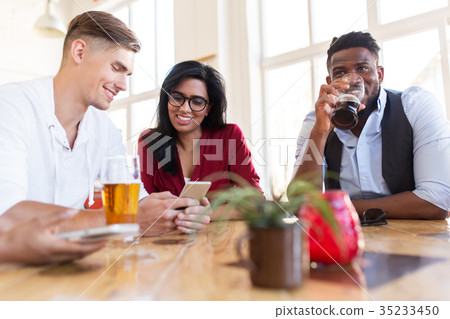 happy friends with smartphone drinking beer at bar 35233450