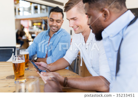 male friends with tablet pc drinking beer at bar male friends with tablet pc drinking beer at bar 35233451