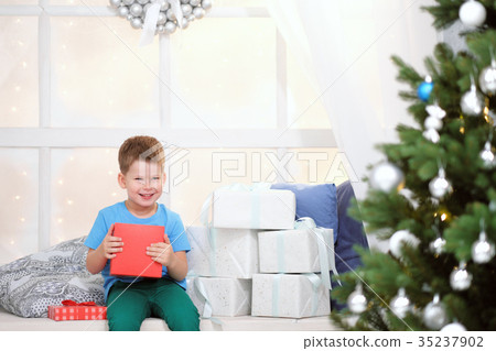 Boy opens a box with a Christmas present Boy opens a box with a Christmas present 35237902