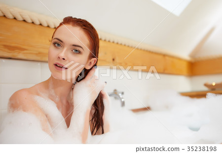Portrait of happy young woman playing with foam in bathtub Portrait of happy young woman playing with foam in bathtub 35238198