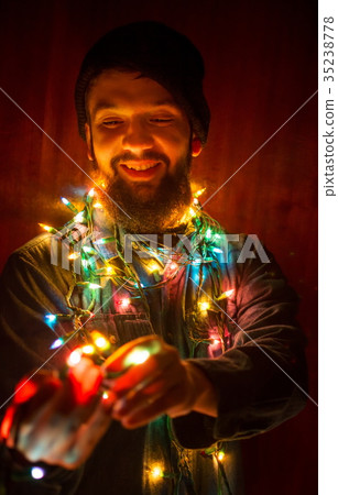 Bearded man wrapped in Christmas lights Bearded man wrapped in Christmas lights 35238778