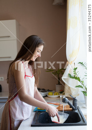 girl housewife washes dirty dishes in the kitchen girl housewife washes dirty dishes in the kitchen 35244375